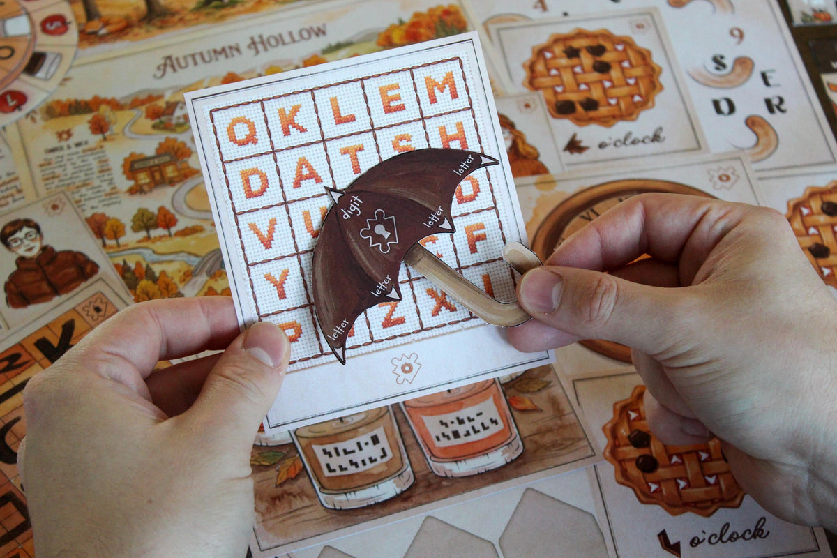 Hands holding an interactive umbrella decoder puzzle from Cozy Autumn Escape Room, a printable fall-themed escape room for teens, adults, families, and puzzle lovers. The brown paper umbrella is placed over a letter grid to identify specific letters and a digit, while the Autumn Hollow map, pumpkin clock, candles, apple pie cards, and character clues appear in the background. This DIY escape room combines visual alignment, observation, decoding, and hands-on seasonal puzzle solving.