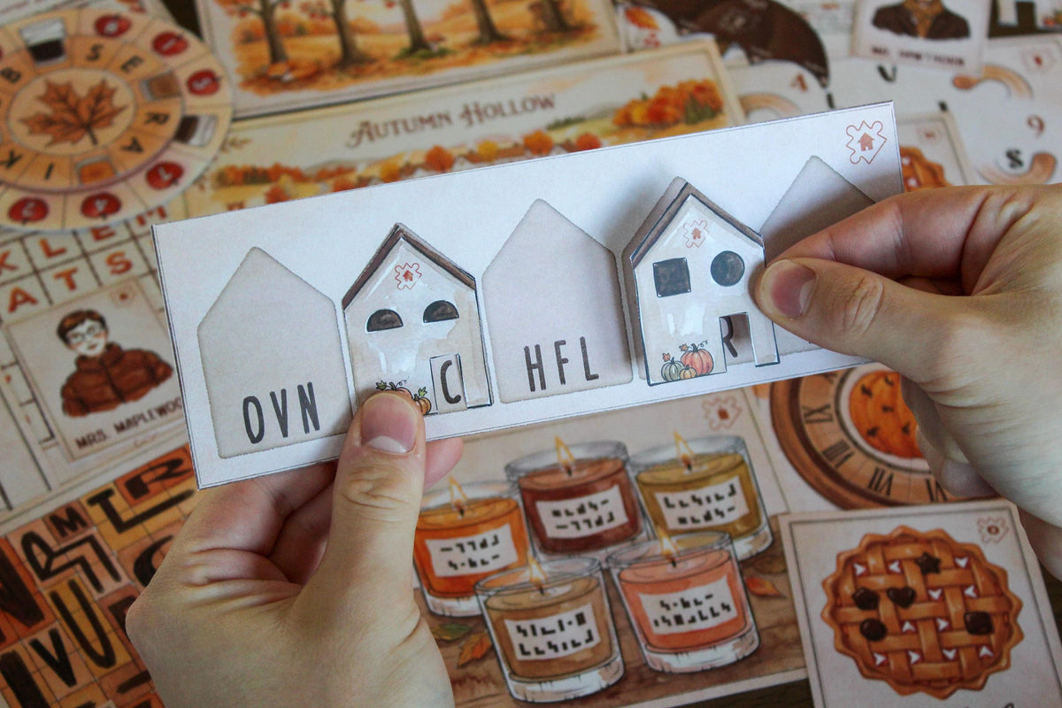 Hands holding an interactive Maple Lane house puzzle from Cozy Autumn Escape Room, a printable fall-themed escape room for teens, adults, families, and puzzle lovers. The folded house pieces reveal hidden letters and symbols used to solve one of the Autumn Hollow challenges. Seasonal game materials in the background include illustrated candles, a pumpkin clock, apple pie cards, character clues, and the village map, highlighting the game’s hands-on logic, deduction, and cozy autumn gameplay.