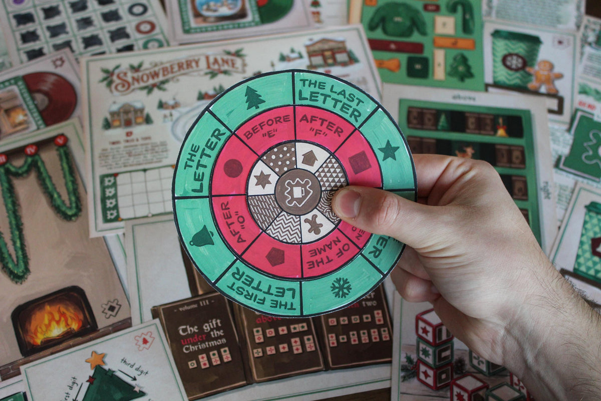 Close-up of a hand holding a three-layer rotating decoder wheel from the Cozy Christmas printable escape room, with instructions such as “the first letter” and “the last letter” arranged around festive symbols and patterns. In the background are illustrated Snowberry Lane game materials including the village map, Advent Workshop fireplace, Christmas books, festive cups, puzzle cards, blocks, and other tactile components from the MysteryLocks Cozy Christmas Escape Room.