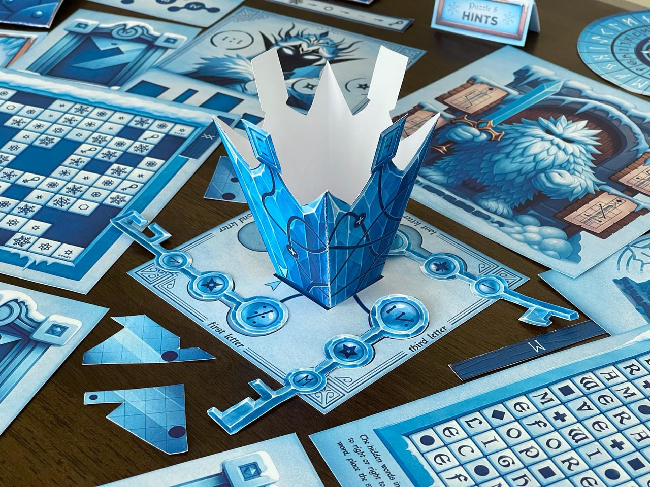 The Snow Queen printable escape room by MysteryLocks displayed on a table with icy blue puzzles, maze cards, and a 3D paper crown centerpiece. This winter-themed DIY escape room kit includes logic puzzles, secret keys, and illustrated clue sheets inspired by the frozen kingdom. Ideal for families, classrooms, or game nights, it offers a creative at-home escape experience filled with storytelling, hands-on assembly, and interactive problem-solving fun.