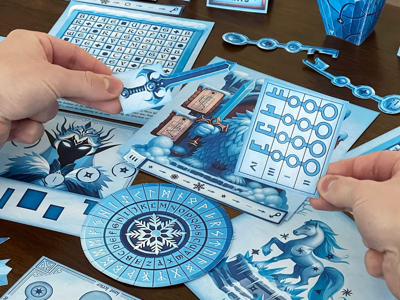 Hands holding puzzle pieces from The Snow Queen printable escape room by MysteryLocks, featuring a glowing blue sword and a key cipher sheet. The table is filled with icy logic puzzles, runic decoder wheels, and illustrated winter scenes. This DIY printable escape room lets players solve clues, unlock codes, and uncover the secrets of the frozen realm — perfect for families, classrooms, or escape room fans seeking a creative winter puzzle adventure at home.