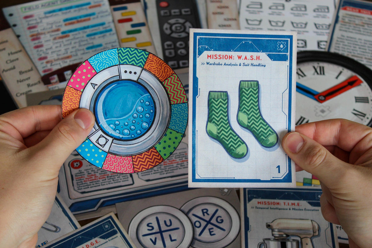 Player holding the colorful washing-machine cipher disk and W.A.S.H. mission card from Your Home Is an Escape Room. The printable escape room uses clothing cards, laundry symbols, patterns, colors, a real washing machine location, and interactive paper components to reveal hidden answers. Designed for kids, teens, and families, this spy-themed DIY puzzle game transforms everyday household areas into secret-agent missions that can be completed around the home.
